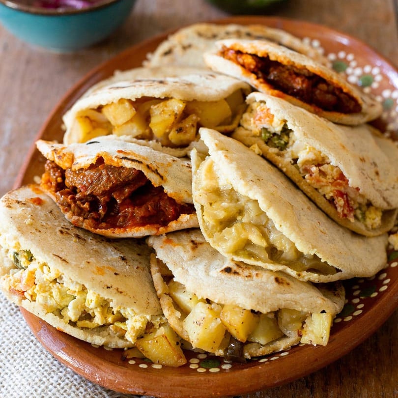 A platter of Toortugas Mexican Torteria gorditas with various savory fillings like potatoes, meat, and eggs.